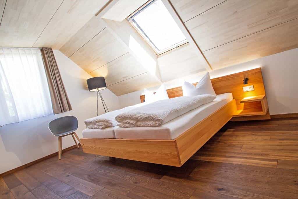 Attic hotel room with wooden bed, skylight, and dark wood floor in Waldshut.