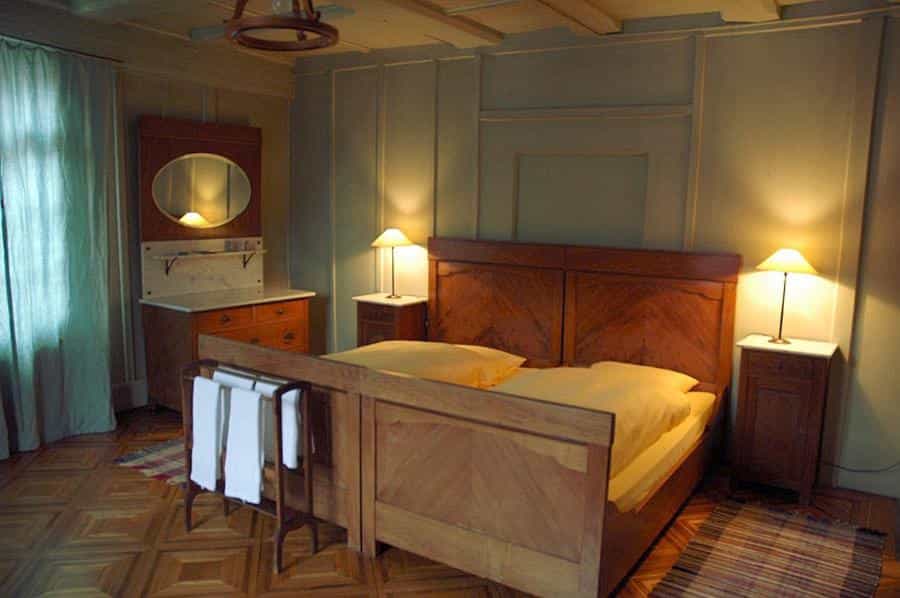 Wooden bedroom with double bed, dresser, and bedside lamps at Hirschen Stammheim, Stein am Rhein.