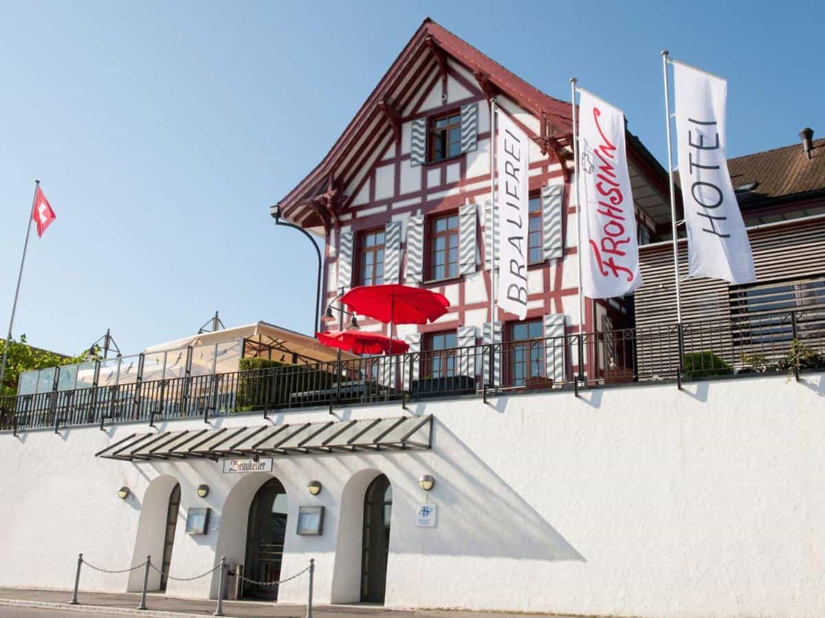 Hotel Brauerei Frohsinn building in Arbon with Swiss flag and outdoor terrace seating.