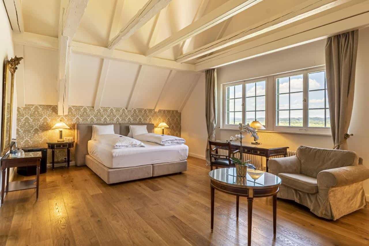 Hotel room with exposed beams, wood floor, large bed, and view from window in Kreuzlingen.
