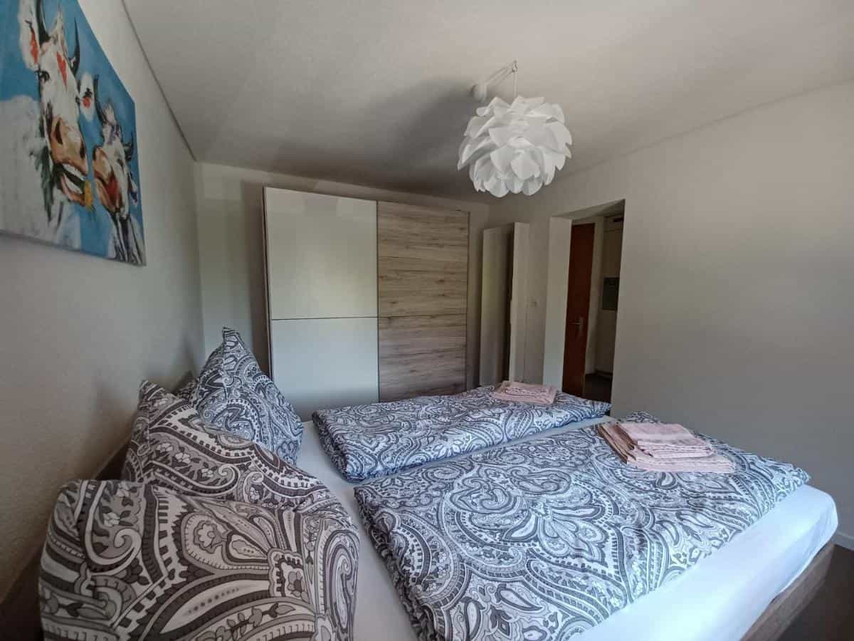 Bedroom with twin beds, paisley bedding, modern wardrobe, and cow art print.