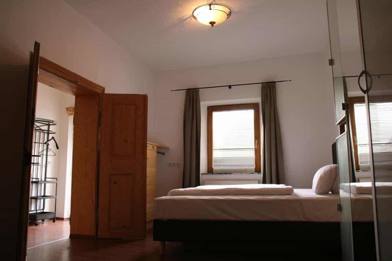 Bedroom in Hotel Goldene Krone with made bed, wooden doors, and window with blinds.