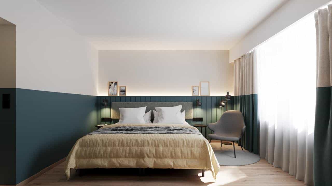 Hotel room with queen bed, blue accent wall, and bright window with sheer curtains at City Hotel Biel-Bienne.