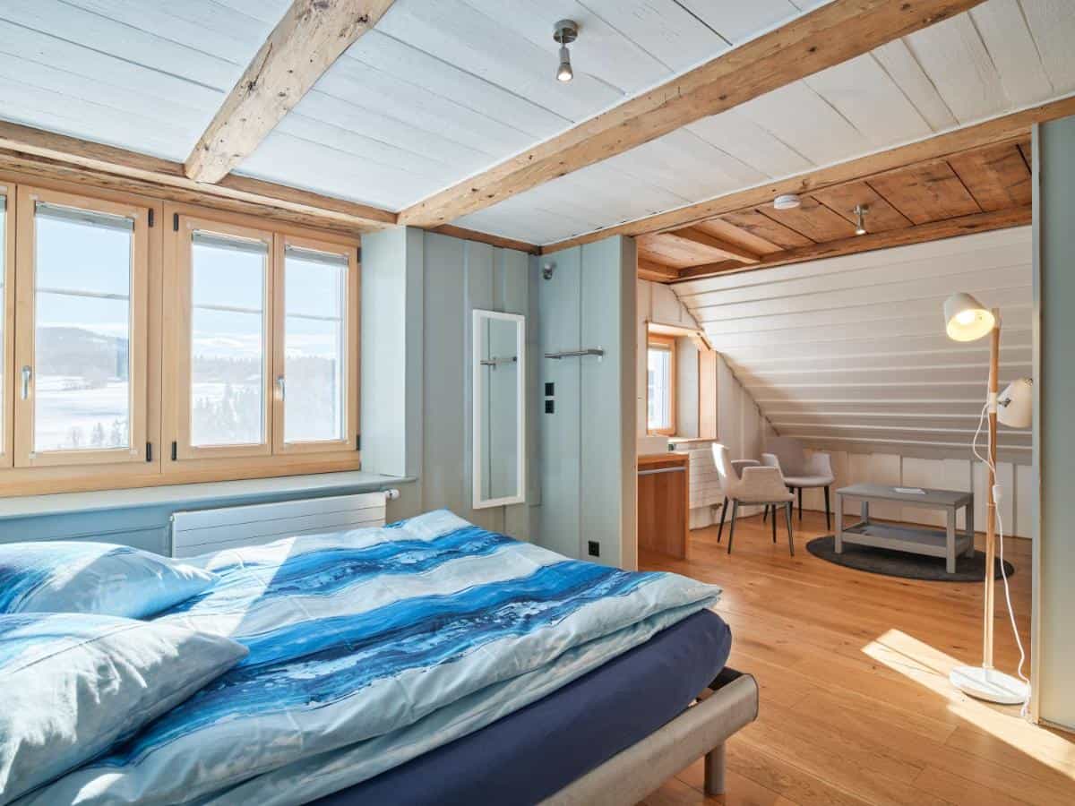 Bedroom with blue bedding, wood floors, and view of snowy landscape in Yverdon-Les-Bains Jurabelle.