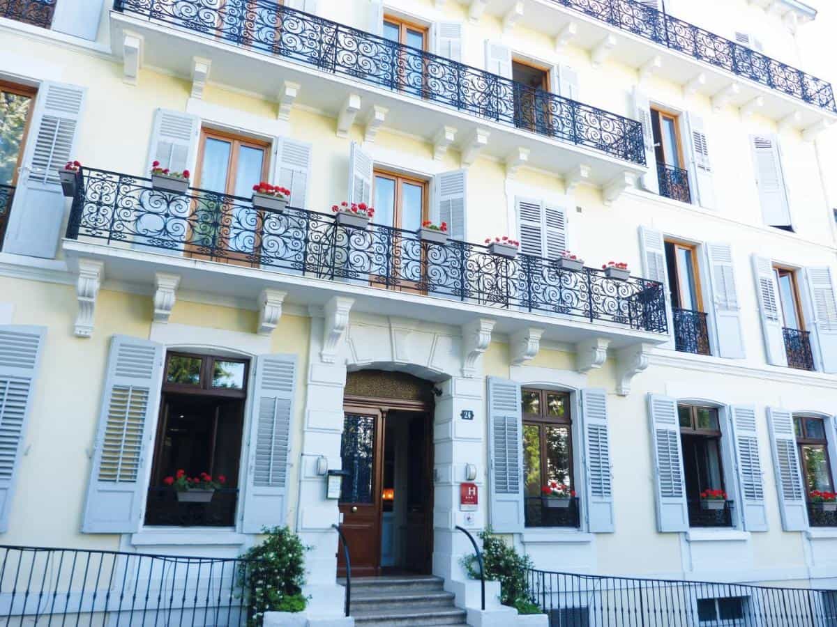 Hotel Gallia in Aix-les-Bains facade with yellow walls, white trim, and wrought iron balconies.