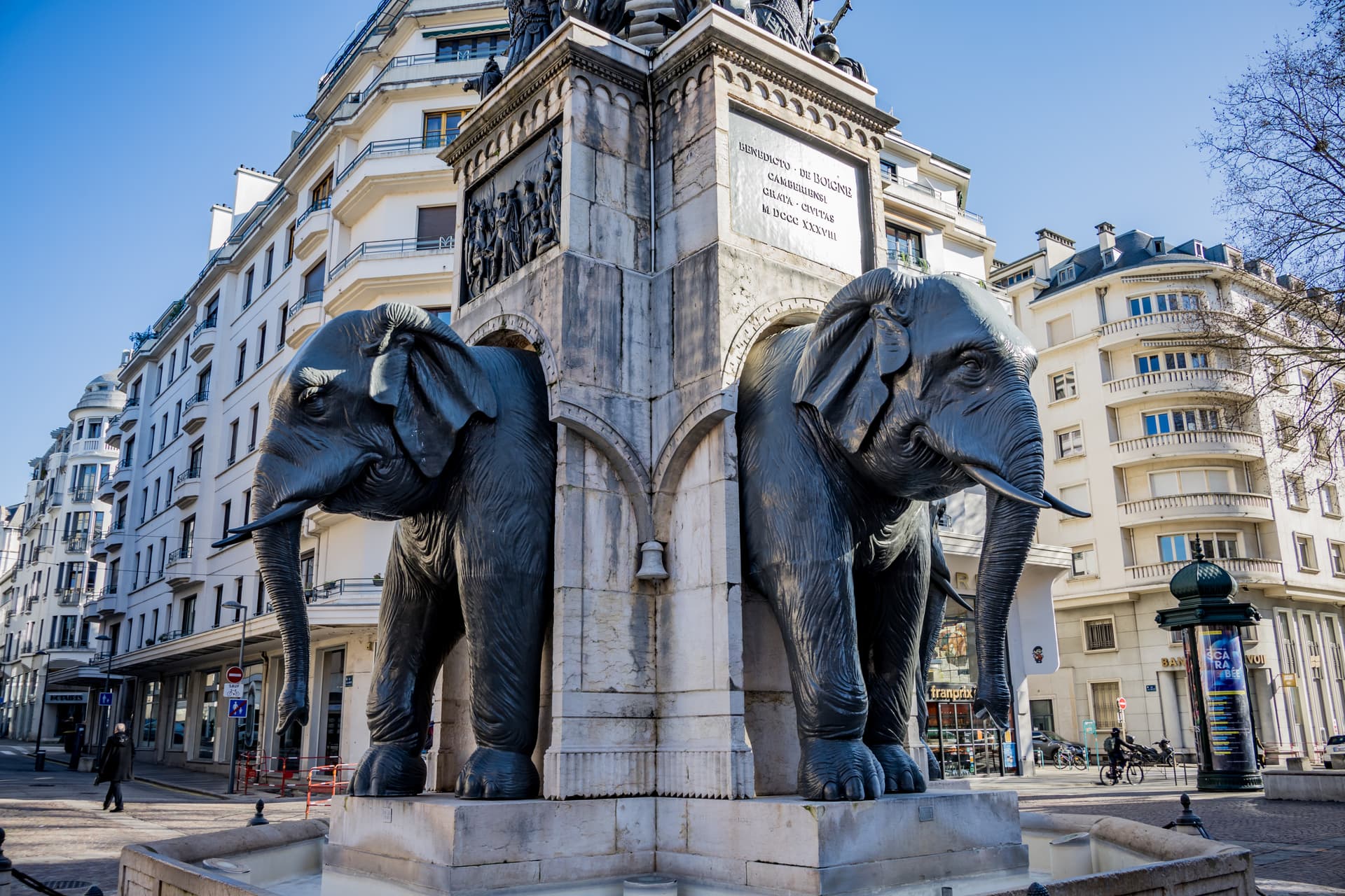 Elephant statues on the Fontaine des Éléphants monument in Chambéry against white buildings.