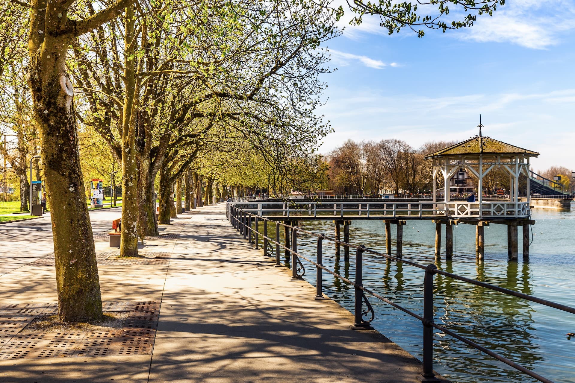 Promenade along Lake Constance at Bregenz with trees and lakeside gazebo on stilts.