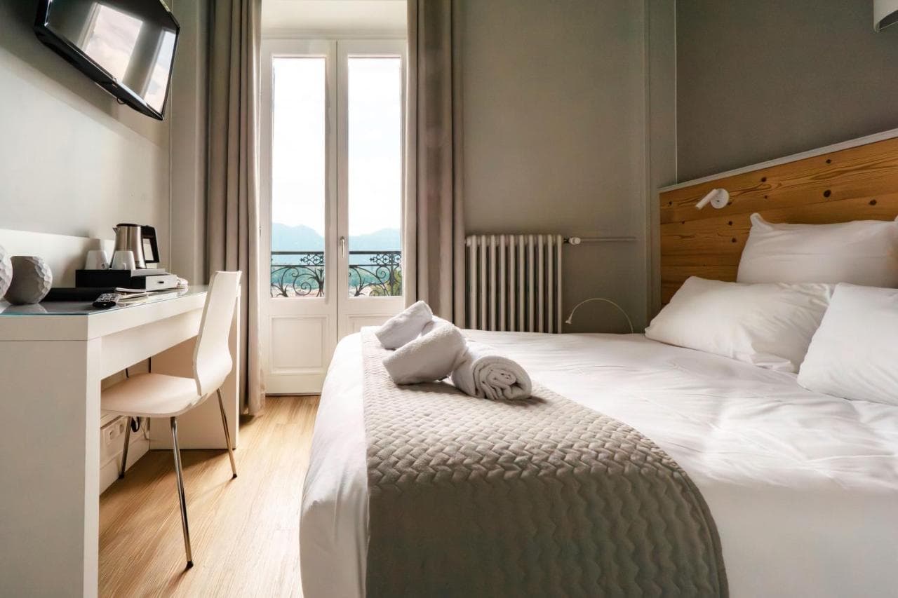 Hotel Gallia Aix-les-Bains room with white bedding and balcony view of mountains.