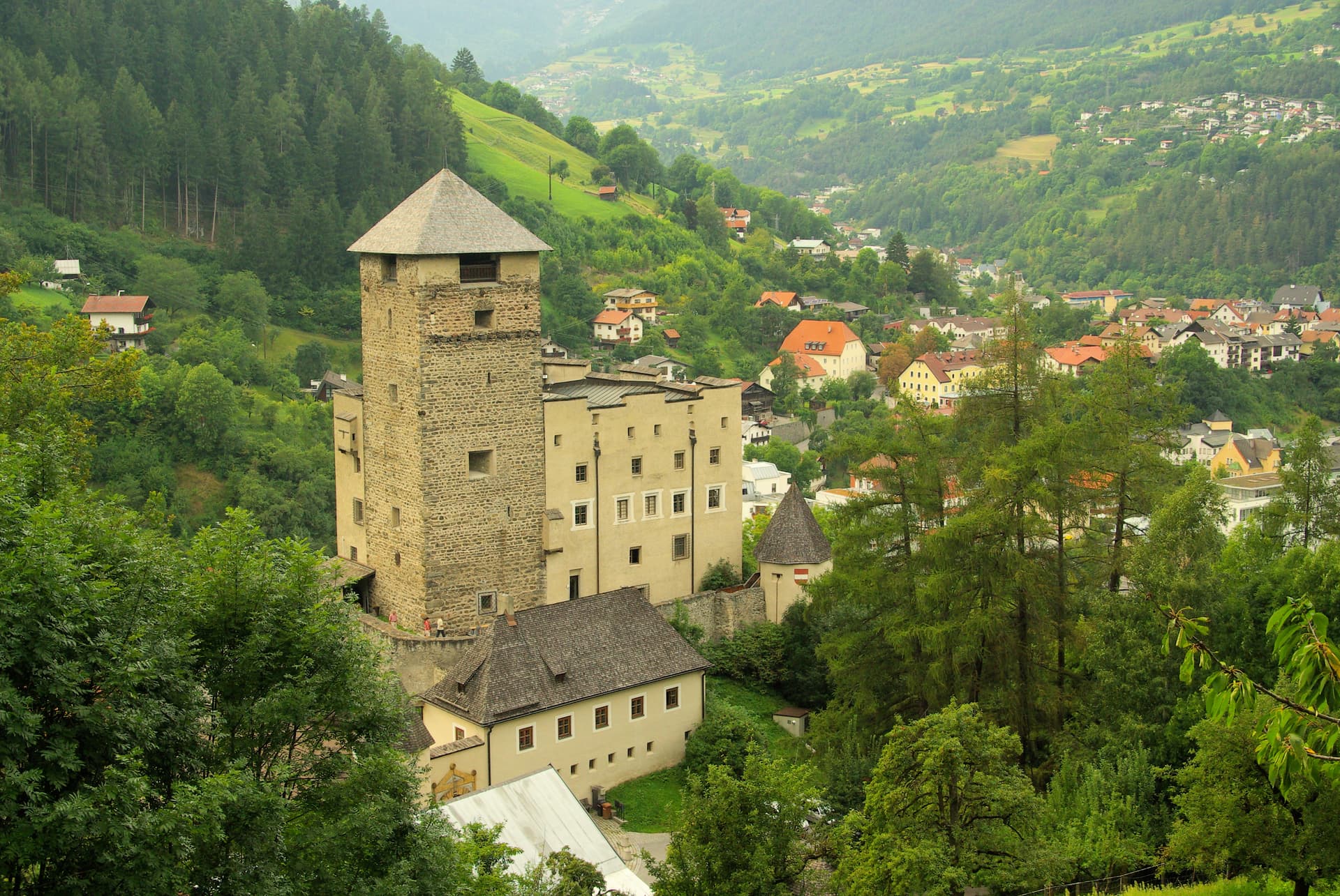 Landeck Castle overlooking a green valley town nestled in the Austrian Alps.