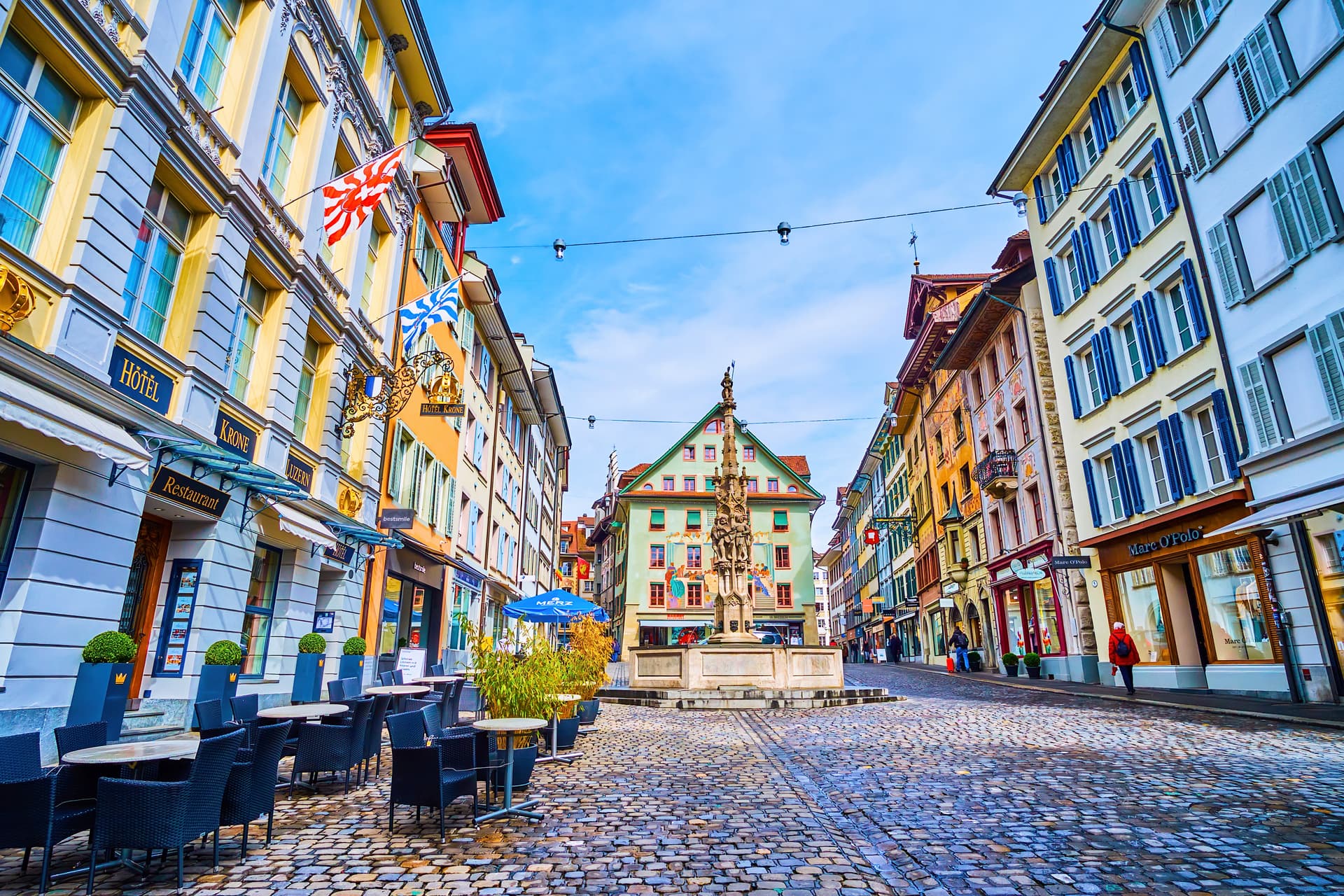 Outdoor restaurant seating on cobblestones in Weinmarkt square, Lucerne, Switzerland.