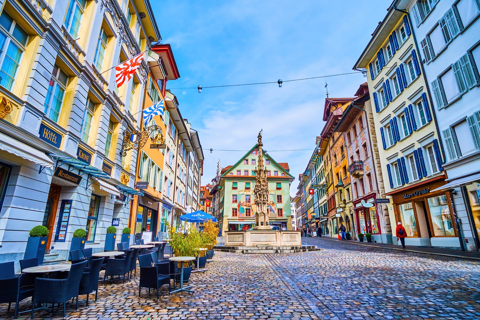Outdoor restaurant seating on cobblestones in Weinmarkt square, Lucerne, Switzerland.